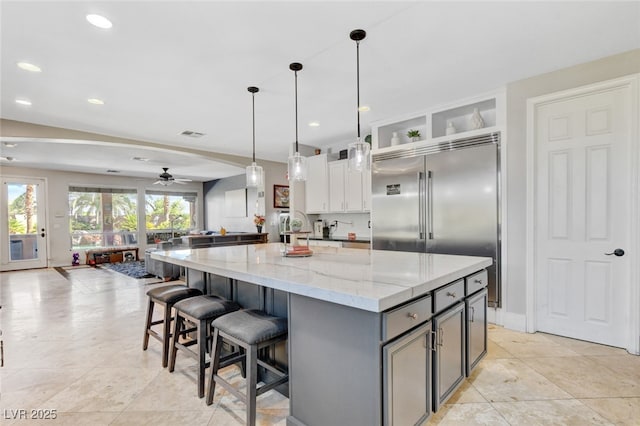 10960 Bethel Park Ct, Las Vegas, NV 89141 - kitchen featuring ceiling fan, gray cabinets, light stone countertops, a kitchen island, and stainless steel built in refrigerator