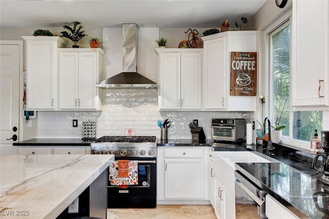 10960 Bethel Park Ct, Las Vegas, NV 89141 - kitchen featuring wall chimney range hood, stainless steel stove, dishwasher, dark stone counters, and plenty of natural light