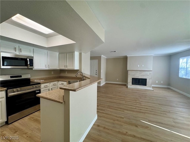 8600 W Charleston Blvd Unit 2161, Las Vegas, NV 89117 - kitchen with stainless steel appliances, a peninsula, light wood-style flooring, light stone countertops, and ornamental molding