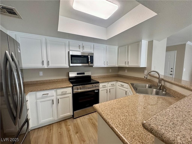 8600 W Charleston Blvd Unit 2161, Las Vegas, NV 89117 - kitchen featuring stainless steel appliances, white cabinets, light wood-style floors, light countertops, and a tray ceiling