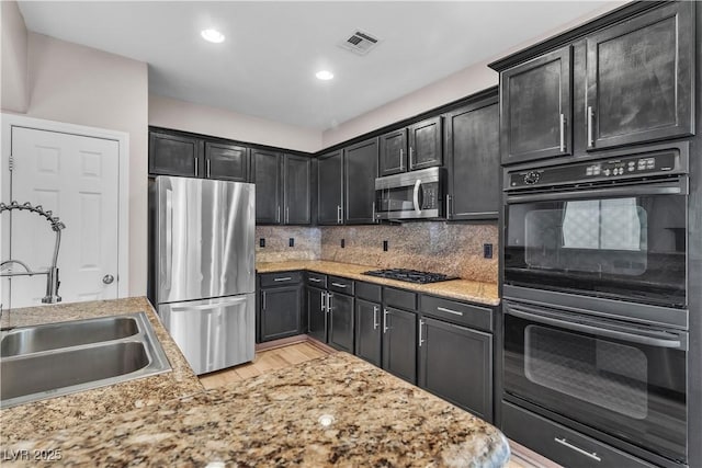 5001 Pounding Surf Ave, Las Vegas, NV 89131 - kitchen with stainless steel appliances, light wood-type flooring, decorative backsplash, recessed lighting, and dark cabinets