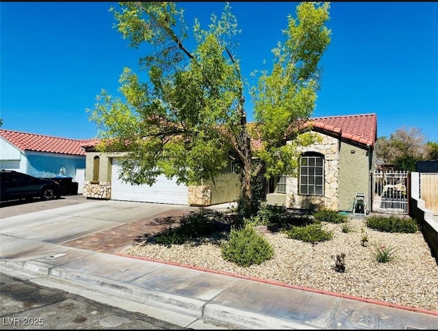 4216 Famoso Dr, North Las Vegas, NV 89032 - mediterranean / spanish-style house with an attached garage, a tile roof, driveway, stone siding, and stucco siding