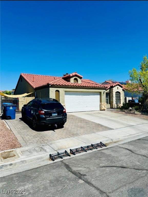4216 Famoso Dr, North Las Vegas, NV 89032 - view of front of property featuring driveway, a garage, a tile roof, stucco siding, and stone siding