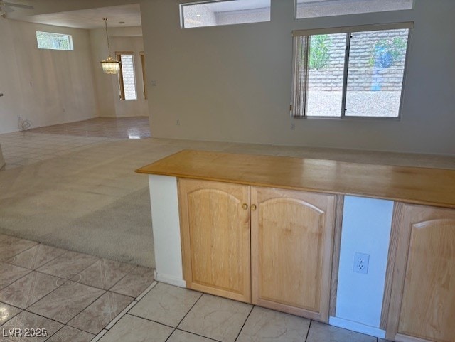 3013 Abercorn Dr, Las Vegas, NV 89134 - kitchen with light brown cabinetry, open floor plan, plenty of natural light, and a chandelier