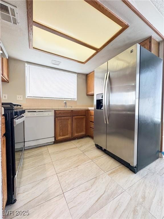 6437 Peachwood Rd, Las Vegas, NV 89108 - kitchen featuring stainless steel appliances, brown cabinetry, and light countertops