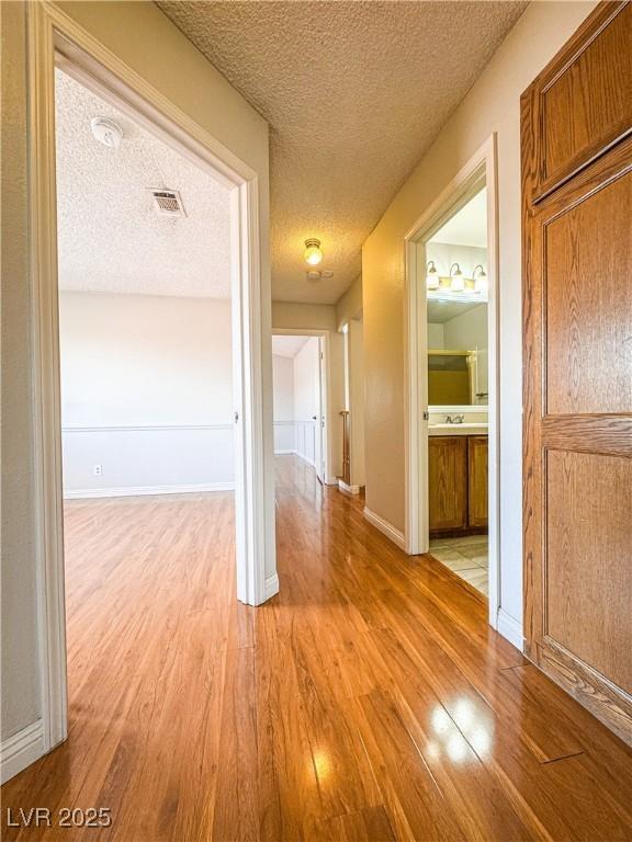 6437 Peachwood Rd, Las Vegas, NV 89108 - hall featuring light wood-style flooring and a textured ceiling