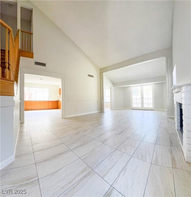 6437 Peachwood Rd, Las Vegas, NV 89108 - unfurnished living room with high vaulted ceiling, a brick fireplace, stairs, and light tile patterned floors