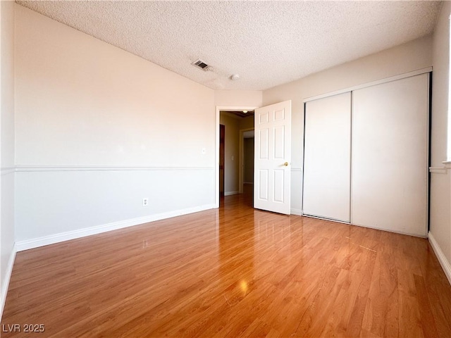 6437 Peachwood Rd, Las Vegas, NV 89108 - unfurnished bedroom featuring light wood-style flooring, a textured ceiling, and a closet