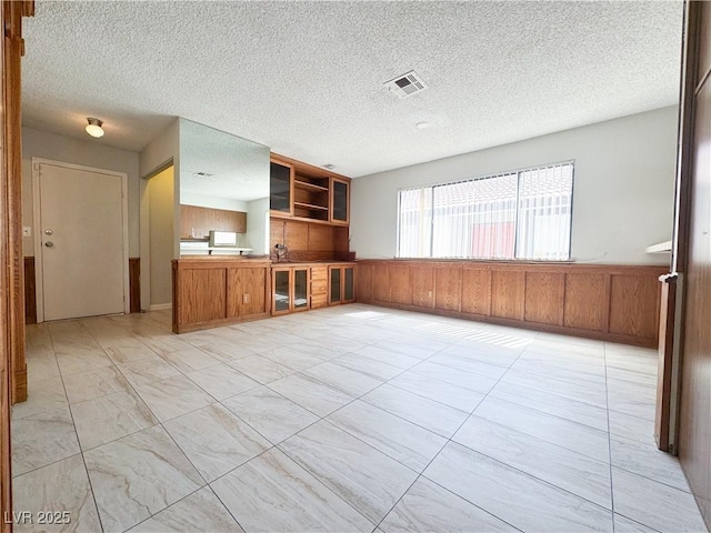 6437 Peachwood Rd, Las Vegas, NV 89108 - unfurnished living room with a wainscoted wall, wood walls, and a textured ceiling