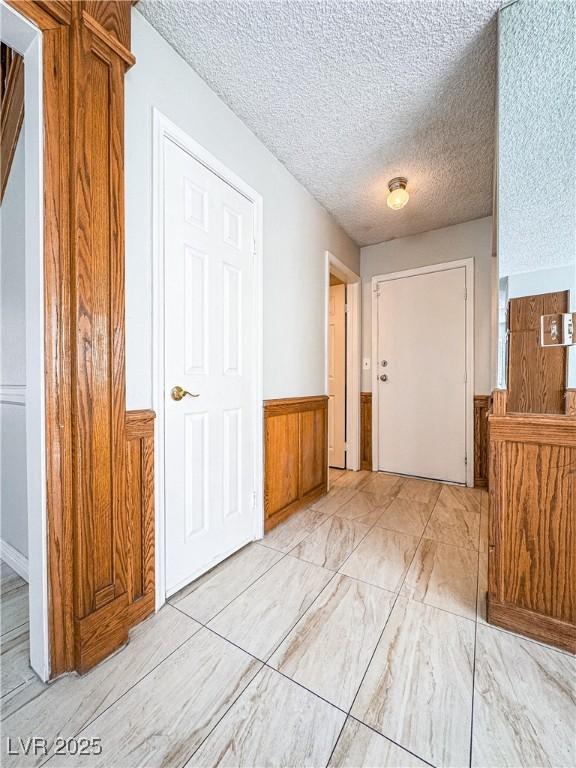 6437 Peachwood Rd, Las Vegas, NV 89108 - foyer featuring a wainscoted wall, a textured ceiling, and wood walls