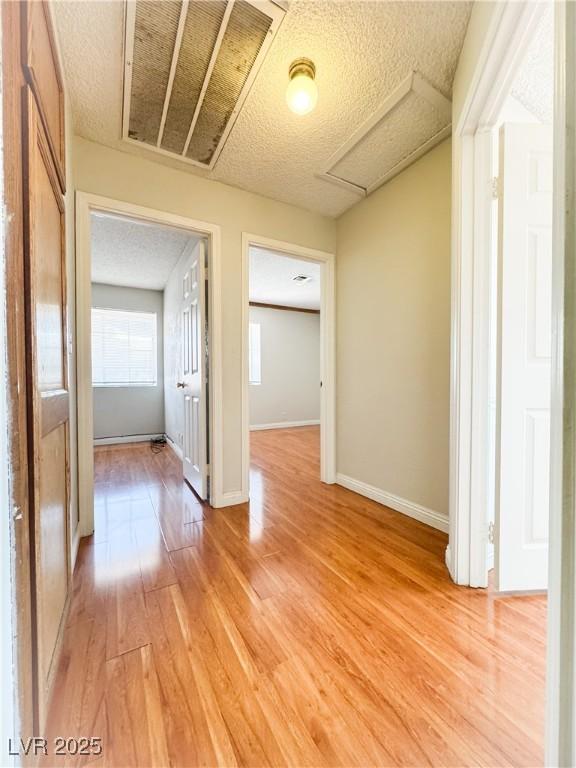 6437 Peachwood Rd, Las Vegas, NV 89108 - corridor with attic access, light wood finished floors, and a textured ceiling