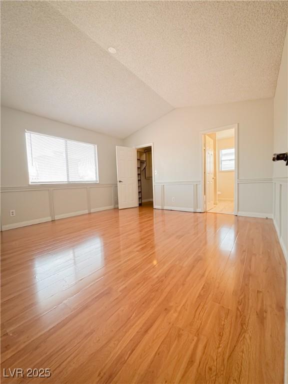 6437 Peachwood Rd, Las Vegas, NV 89108 - unfurnished living room with a textured ceiling, light wood-type flooring, a wainscoted wall, and a decorative wall