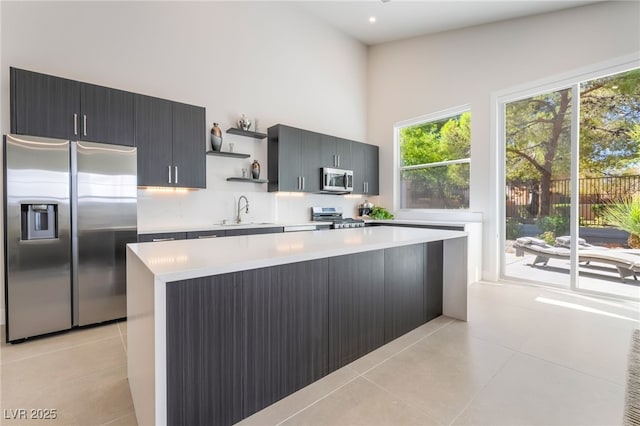 9332 Sienna Vista Dr, Las Vegas, NV 89117 - kitchen with appliances with stainless steel finishes, open shelves, light tile patterned flooring, light countertops, and a high ceiling