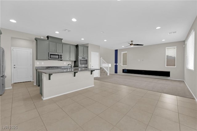 8969 Rice Peak St, Las Vegas, NV 89148 - kitchen with appliances with stainless steel finishes, light carpet, a kitchen breakfast bar, a center island with sink, and gray cabinetry