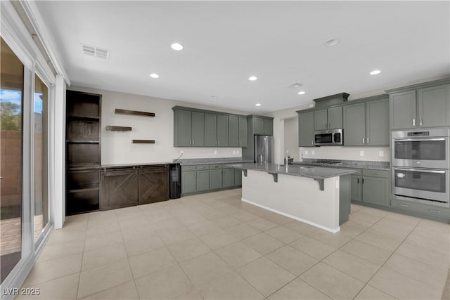 8969 Rice Peak St, Las Vegas, NV 89148 - kitchen with appliances with stainless steel finishes, a kitchen bar, stone counters, a kitchen island with sink, and recessed lighting