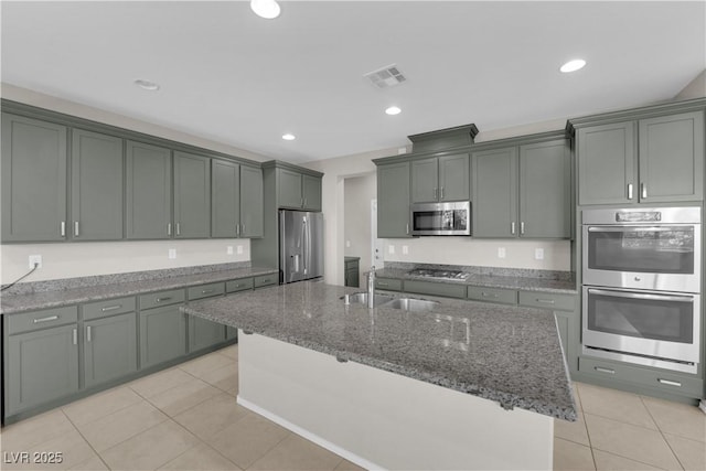 8969 Rice Peak St, Las Vegas, NV 89148 - kitchen with appliances with stainless steel finishes, light tile patterned floors, stone counters, an island with sink, and recessed lighting