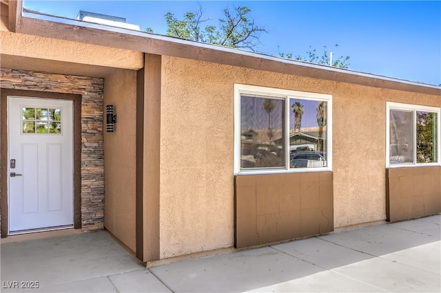 3887 Delling Ct, Las Vegas, NV 89104 - doorway to property featuring stone siding, stucco siding, and a patio area