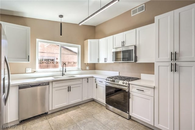 3887 Delling Ct, Las Vegas, NV 89104 - kitchen with appliances with stainless steel finishes, white cabinetry, light countertops, hanging light fixtures, and light tile patterned floors