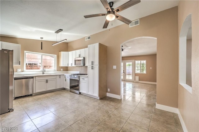 3887 Delling Ct, Las Vegas, NV 89104 - kitchen featuring stainless steel appliances, a ceiling fan, arched walkways, and white cabinetry