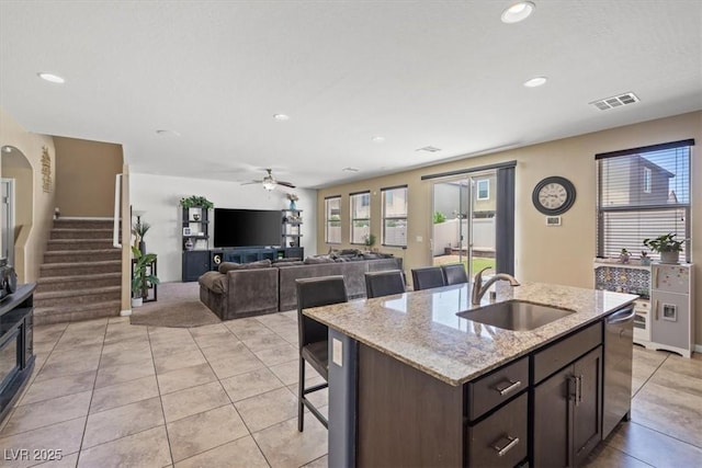 5309 Golden Melody Ln, North Las Vegas, NV 89081 - kitchen with stainless steel dishwasher, recessed lighting, dark brown cabinetry, a center island with sink, and light tile patterned floors