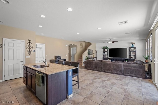 5309 Golden Melody Ln, North Las Vegas, NV 89081 - kitchen with stainless steel dishwasher, a breakfast bar area, a ceiling fan, light tile patterned floors, and a center island with sink