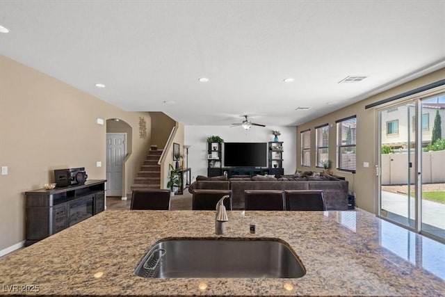 5309 Golden Melody Ln, North Las Vegas, NV 89081 - kitchen featuring light stone counters, ceiling fan, recessed lighting, open floor plan, and arched walkways