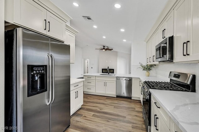 2820 Golf Links Dr, Las Vegas, NV 89134 - kitchen featuring appliances with stainless steel finishes, recessed lighting, a peninsula, light wood-type flooring, and light stone counters