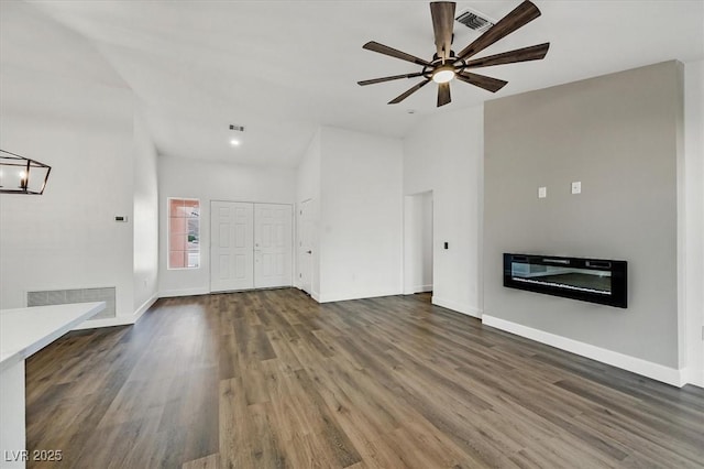 2820 Golf Links Dr, Las Vegas, NV 89134 - unfurnished living room featuring wood finished floors, ceiling fan, a glass covered fireplace, and vaulted ceiling