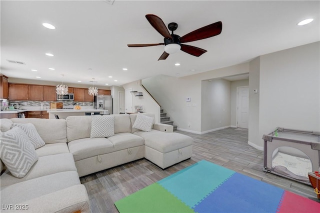 10722 Red Badge Ave, Las Vegas, NV 89166 - living area with recessed lighting, ceiling fan, stairs, light wood-style floors, and a chandelier