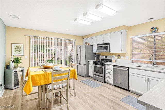 8611 Gabilan Ct, Las Vegas, NV 89123 - kitchen featuring stainless steel appliances, light countertops, light wood-type flooring, and white cabinets