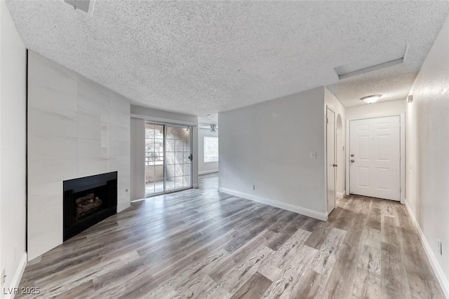 2200 S Fort Apache Rd Unit 2209, Las Vegas, NV 89117 - unfurnished living room featuring a textured ceiling, wood finished floors, a tiled fireplace, and attic access