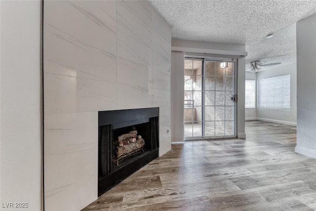 2200 S Fort Apache Rd Unit 2209, Las Vegas, NV 89117 - unfurnished living room with a textured ceiling, a tile fireplace, wood finished floors, and a ceiling fan