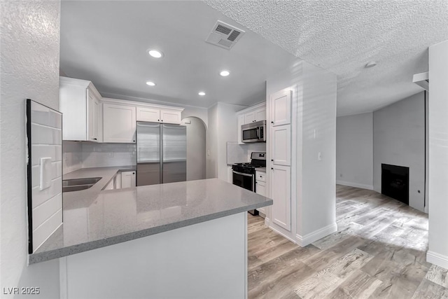 2200 S Fort Apache Rd Unit 2209, Las Vegas, NV 89117 - kitchen featuring stainless steel appliances, light wood-type flooring, arched walkways, white cabinets, and light stone countertops