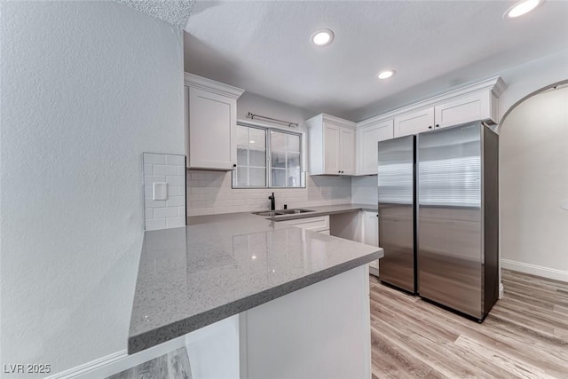 2200 S Fort Apache Rd Unit 2209, Las Vegas, NV 89117 - kitchen with freestanding refrigerator, white cabinetry, backsplash, a textured wall, and light wood-style floors