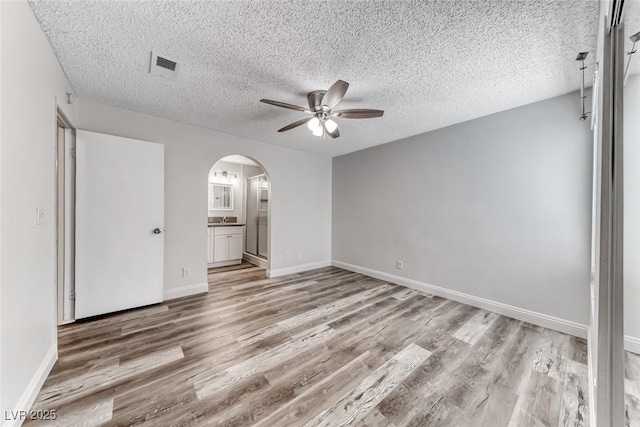 2200 S Fort Apache Rd Unit 2209, Las Vegas, NV 89117 - empty room with a ceiling fan, arched walkways, light wood-style floors, and a textured ceiling