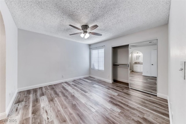 2200 S Fort Apache Rd Unit 2209, Las Vegas, NV 89117 - unfurnished bedroom featuring arched walkways, wood finished floors, a closet, a textured ceiling, and a ceiling fan
