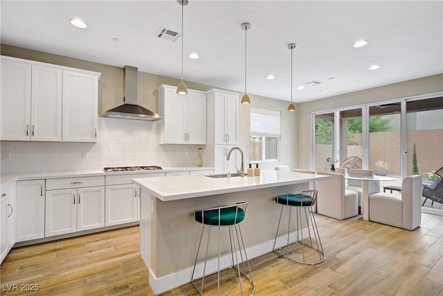 6591 Dove Point Pl, Las Vegas, NV 89130 - kitchen with wall chimney exhaust hood, gas cooktop, light wood finished floors, white cabinets, and recessed lighting