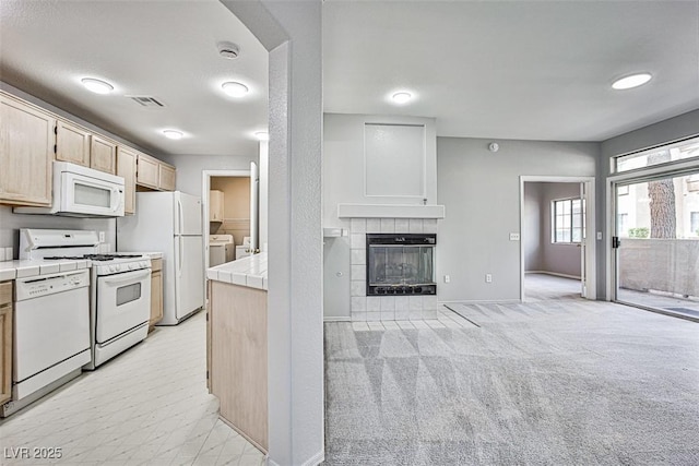 7400 W Flamingo Rd Unit 1051, Las Vegas, NV 89147 - kitchen with white appliances, tile countertops, washing machine and clothes dryer, and a tiled fireplace