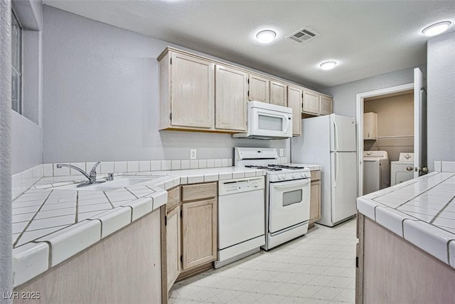 7400 W Flamingo Rd Unit 1051, Las Vegas, NV 89147 - kitchen featuring white appliances, tile counters, independent washer and dryer, light flooring, and a textured wall