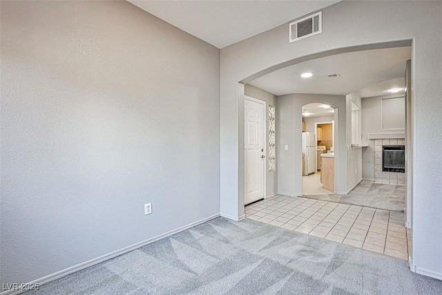 7400 W Flamingo Rd Unit 1051, Las Vegas, NV 89147 - unfurnished room featuring arched walkways, light carpet, light tile patterned floors, and a tiled fireplace
