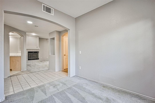 7400 W Flamingo Rd Unit 1051, Las Vegas, NV 89147 - unfurnished living room with arched walkways, light tile patterned flooring, light colored carpet, and a tile fireplace