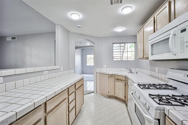 7400 W Flamingo Rd Unit 1051, Las Vegas, NV 89147 - kitchen featuring white appliances, arched walkways, tile counters, and a textured ceiling