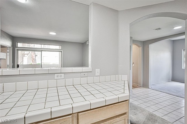7400 W Flamingo Rd Unit 1051, Las Vegas, NV 89147 - kitchen with tile counters, arched walkways, plenty of natural light, light tile patterned flooring, and recessed lighting
