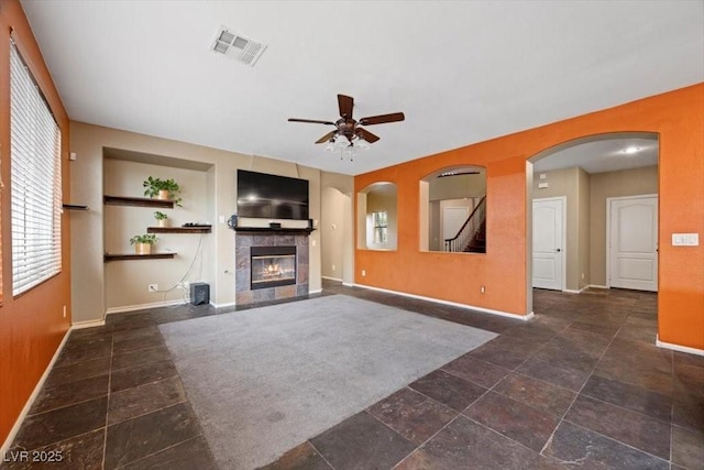 9413 Arcadia Woods Ct, Las Vegas, NV 89149 - unfurnished living room featuring a ceiling fan, a tiled fireplace, and arched walkways