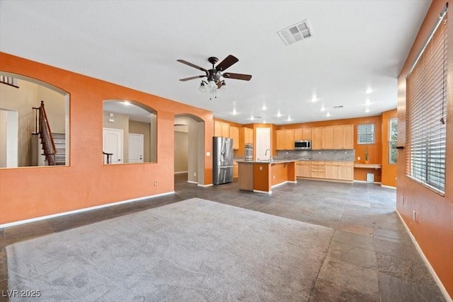 9413 Arcadia Woods Ct, Las Vegas, NV 89149 - kitchen featuring appliances with stainless steel finishes, ceiling fan, open floor plan, light brown cabinets, and a kitchen island with sink