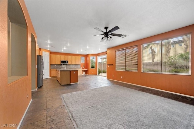 9413 Arcadia Woods Ct, Las Vegas, NV 89149 - kitchen featuring stainless steel appliances, open floor plan, a ceiling fan, arched walkways, and a center island with sink