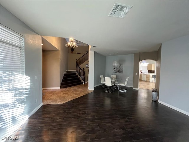 foyer entrance featuring wood finished floors, a chandelier, stairway, and plenty of natural light