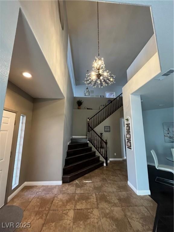 foyer entrance with a chandelier, a towering ceiling, and stairway