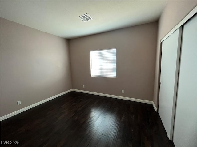 unfurnished bedroom featuring dark wood-style flooring and a closet
