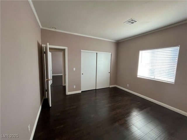 unfurnished bedroom with crown molding, dark wood-style floors, and a closet